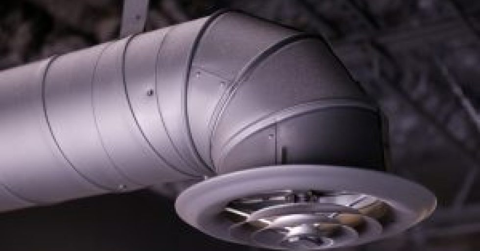 Black industrial air duct and vent or register hanging from an unfinished ceiling in a commercial space under construction